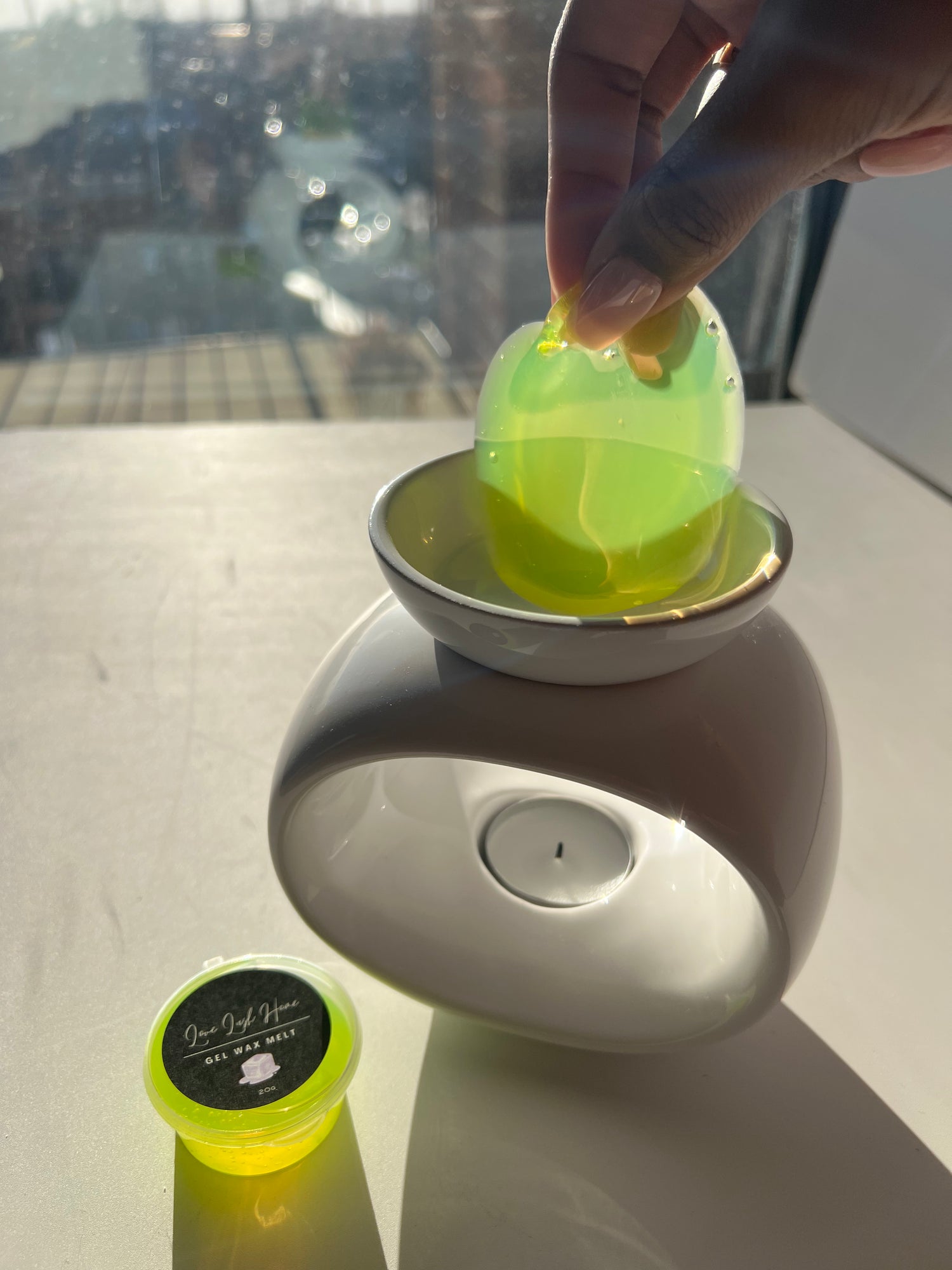 Hand peeling a green gel wax melt product out of a wax melt burner 